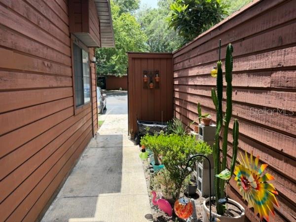 A narrow concrete walkway leads between a wooden building and a privacy fence — 845 SW 55TH TERRACE, GAINESVILLE, FL