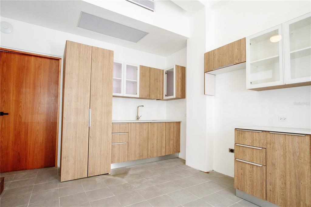 A kitchen features light wood cabinets, white countertops, and gray tile flooring — 319 RECINTO SUR STREET UNIT 2, SAN JUAN, PR