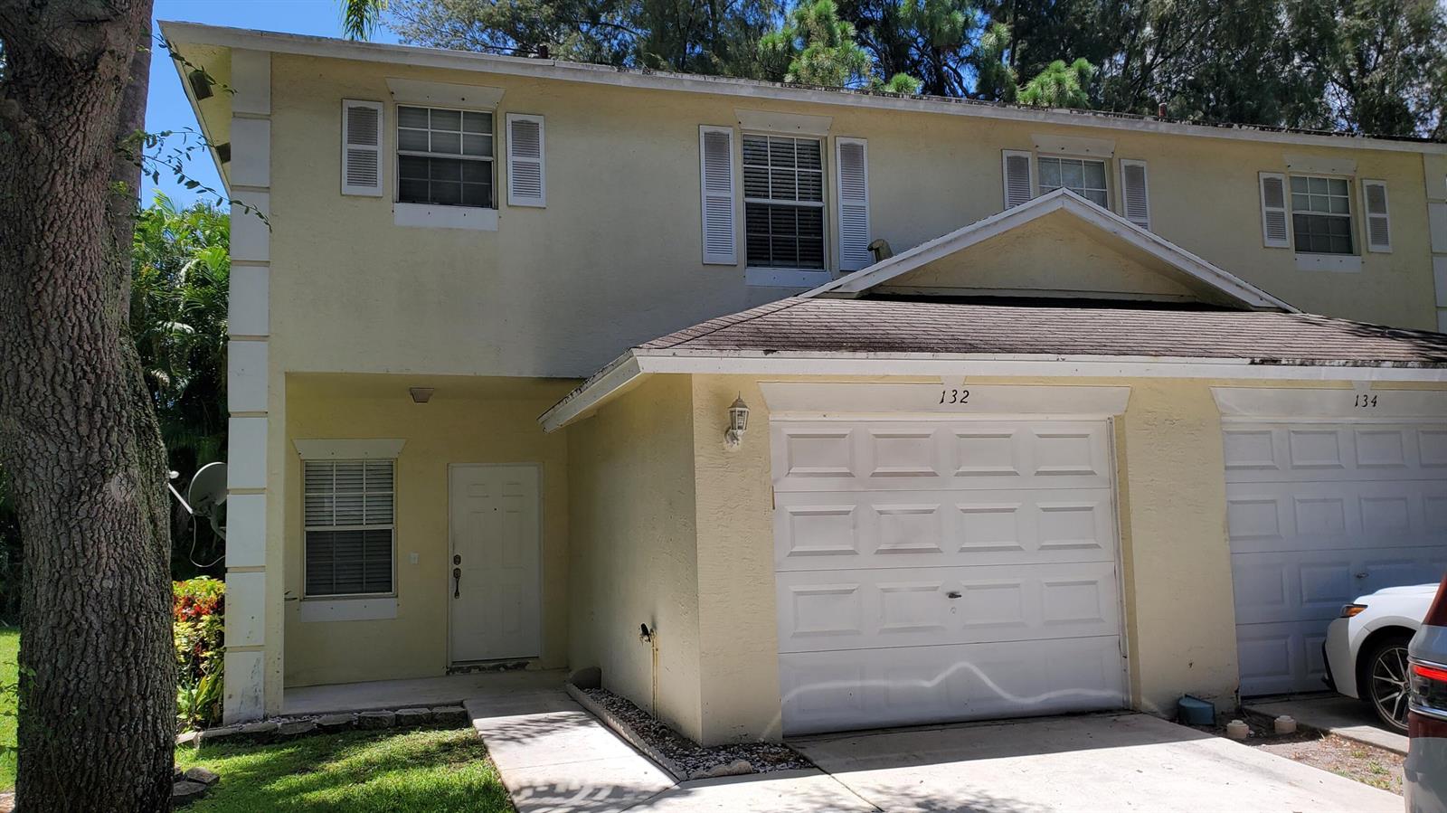 A two-story yellow townhouse with a white garage door and a front entrance — 132 Baldwin Boulevard, FL 33463, FL