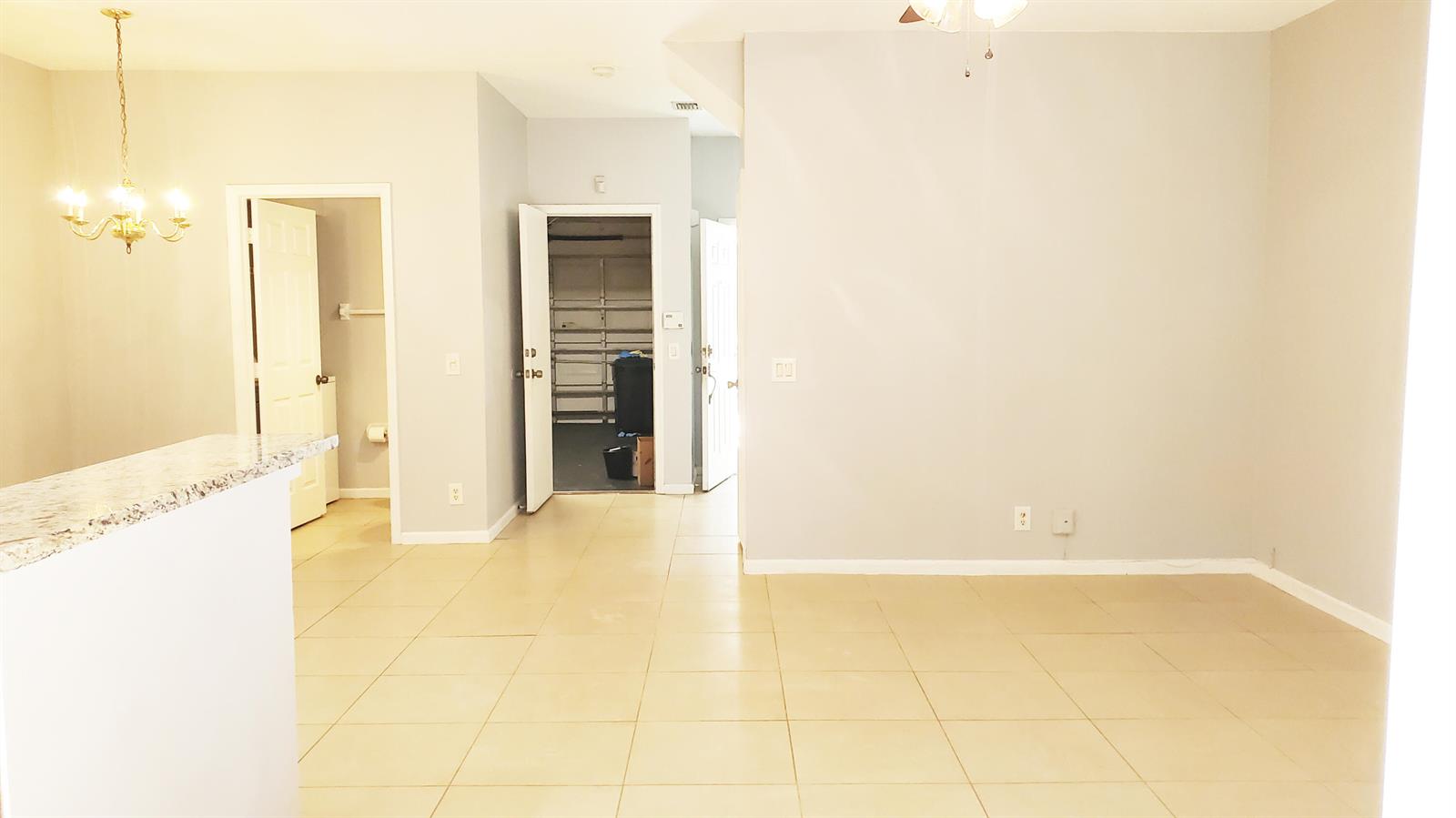 A room with light-colored tile flooring, gray walls, and open doorways leading to other areas — 132 Baldwin Boulevard, FL 33463, FL