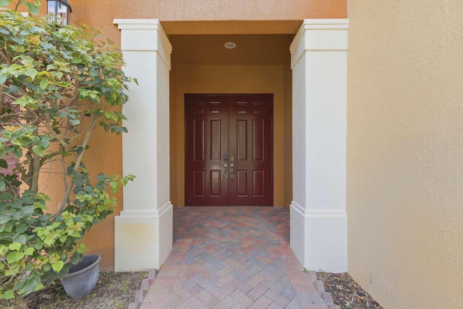 A front entryway with a red double door, white columns, and a brick paver walkway — 9190 Nugent Trail, West Palm Beach FL 33411, WEST PALM BEACH, FL