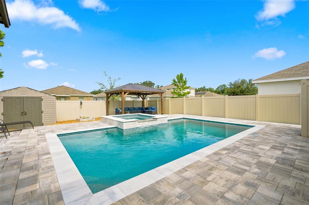 A backyard features a rectangular swimming pool with an attached spa and a wooden gazebo — 6647 SEAWAY DRIVE, BROOKSVILLE, FL