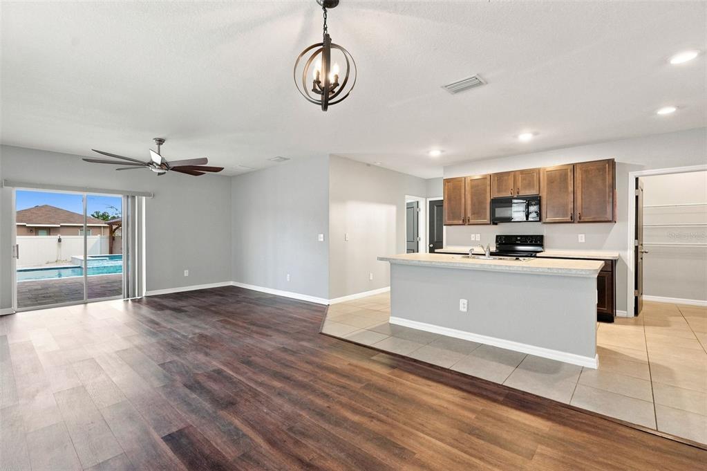 An open-concept kitchen and living area features dark wood flooring, tile, and a sliding door — 6647 SEAWAY DRIVE, BROOKSVILLE, FL