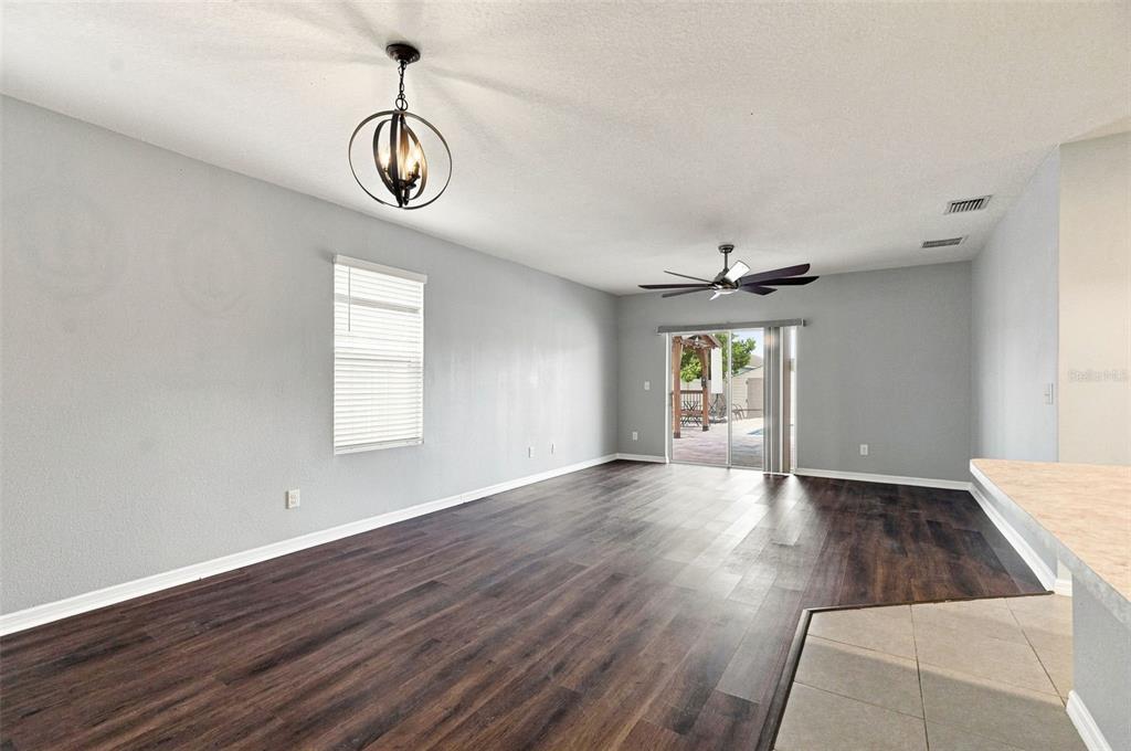 An open living area features dark wood-look flooring, light gray walls, and a sliding glass door — 6647 SEAWAY DRIVE, BROOKSVILLE, FL