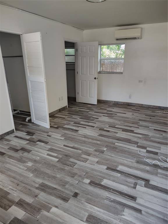 A bedroom features gray wood-look flooring, white walls, a closet, and a wall-mounted air conditioner — 616 GOLF DRIVE, VENICE, FL
