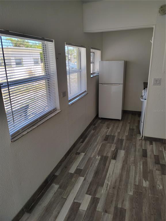 A kitchen area features wood-look flooring, white walls, three windows with blinds, and a refrigerator — 616 GOLF DRIVE, VENICE, FL