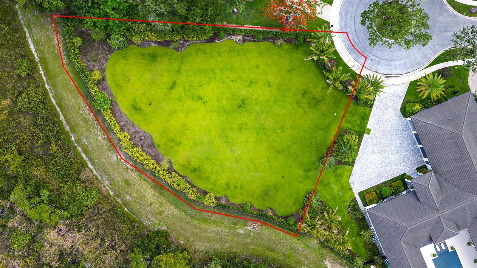 An aerial view shows a large, grassy backyard enclosed by a fence and lush landscaping — 6632 Audubon Trace W, West Palm Beach FL 33412, WEST PALM BEACH, FL