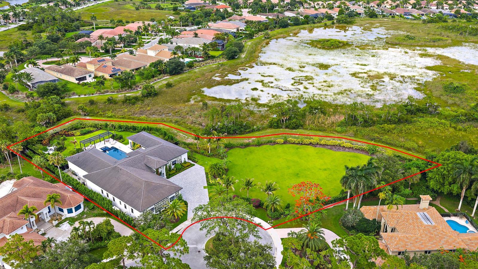 An aerial view shows a modern house with a pool and a large green backyard — 6632 Audubon Trace W, West Palm Beach FL 33412, WEST PALM BEACH, FL