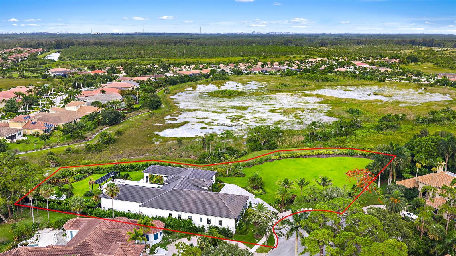 An aerial view shows a house with a large lawn bordering a wetland area — 6632 Audubon Trace W, West Palm Beach FL 33412, WEST PALM BEACH, FL