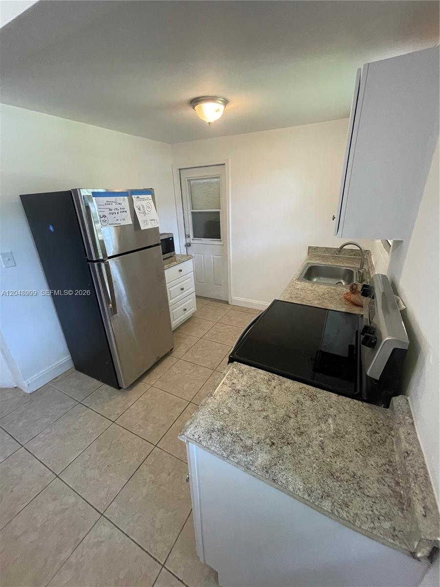 A kitchen features stainless steel appliances, white cabinets, and granite countertops over tiled floors — 453 SW 19th Rd Rear, Miami FL 33129, MIAMI, FL
