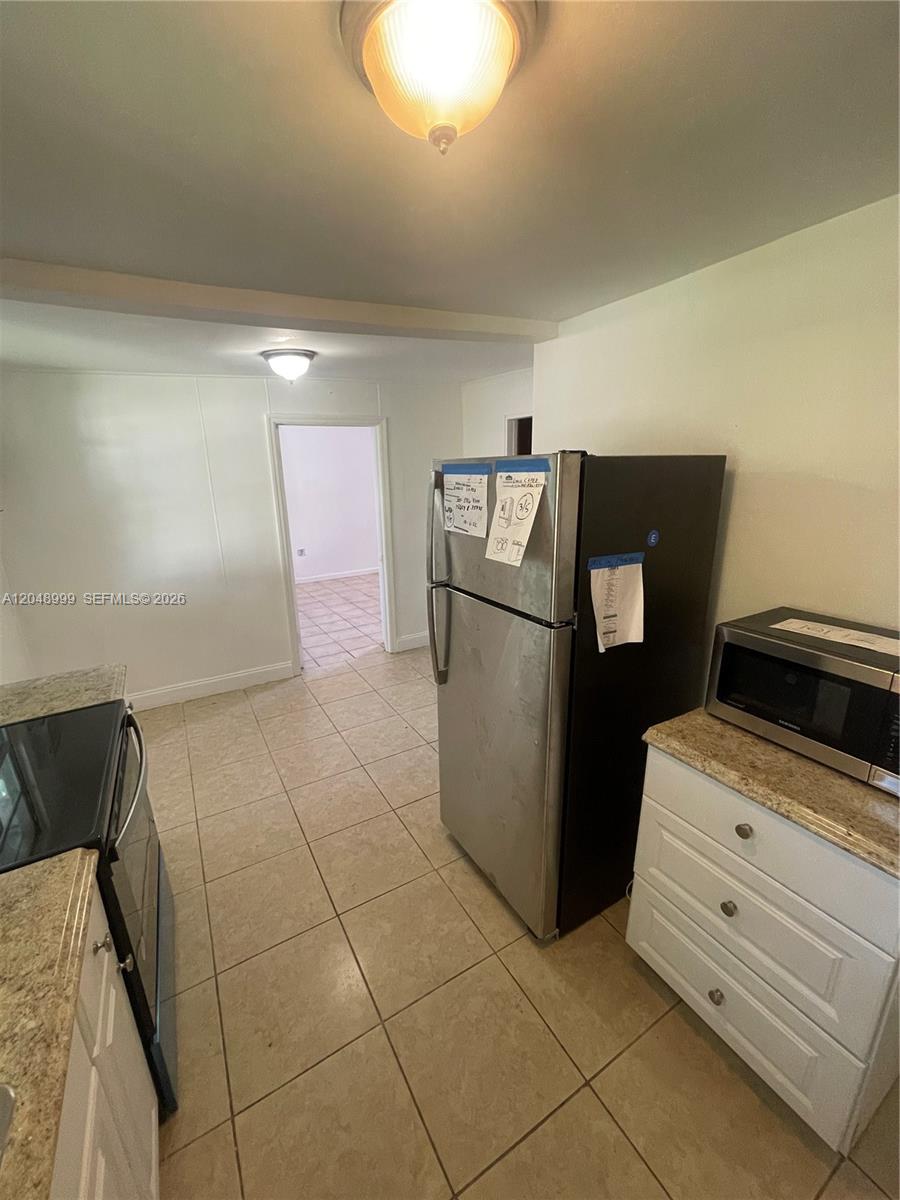 A kitchen features stainless steel appliances, white cabinets, granite countertops, and light-colored floor tiles — 453 SW 19th Rd Rear, Miami FL 33129, MIAMI, FL