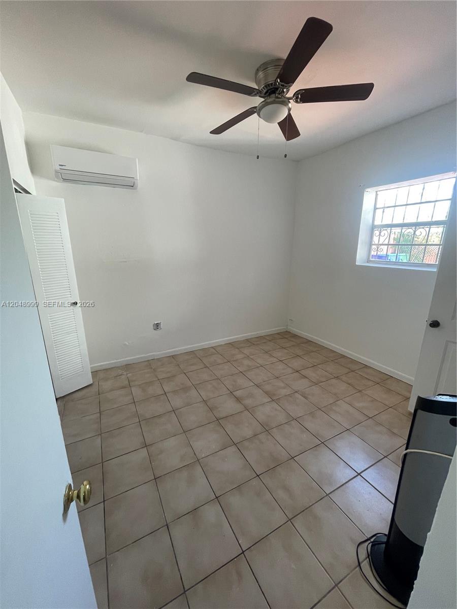 A bedroom with white walls, tile flooring, a ceiling fan, and a wall-mounted air conditioner — 453 SW 19th Rd Rear, Miami FL 33129, MIAMI, FL