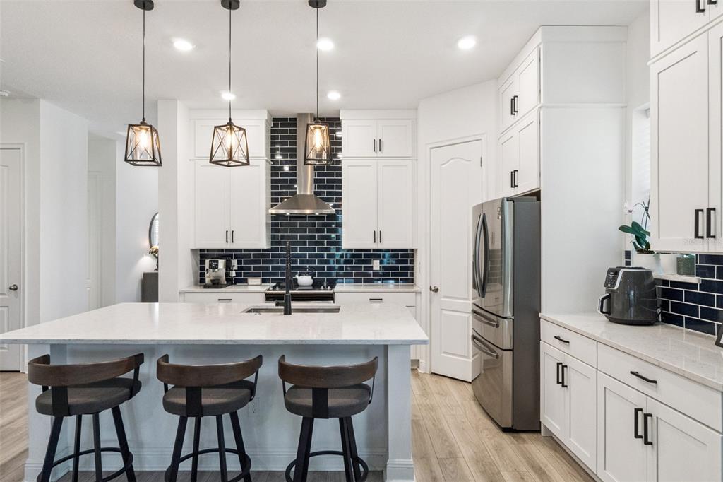 A modern kitchen features white cabinets, a large island, and a dark subway tile backsplash — 6839 BRIDGMAN STREET, ORLANDO, FL
