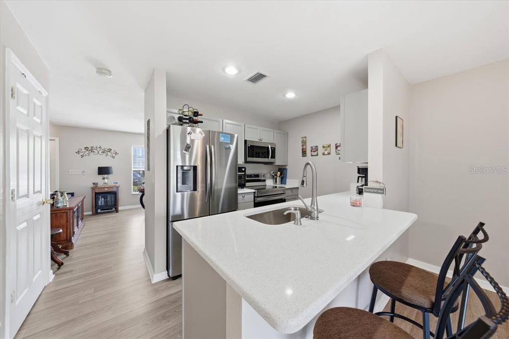 A kitchen features a white quartz island, stainless steel appliances, and light wood-look flooring — 5503 67TH UNIT 18, PINELLAS PARK, FL
