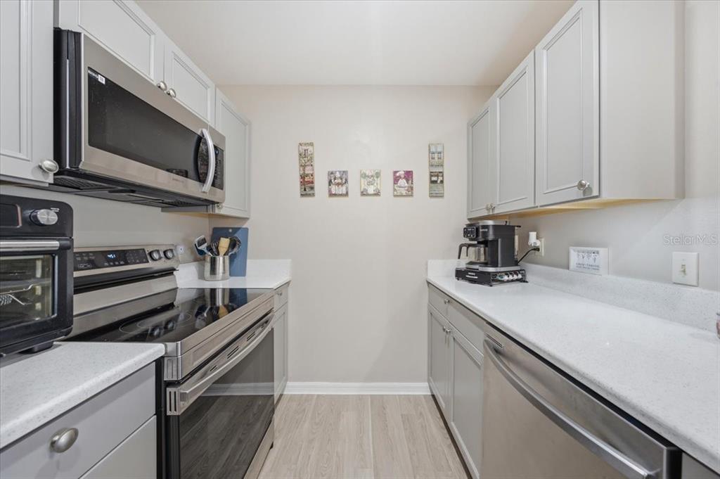 A galley kitchen features gray cabinets, stainless steel appliances, and white countertops — 5503 67TH UNIT 18, PINELLAS PARK, FL