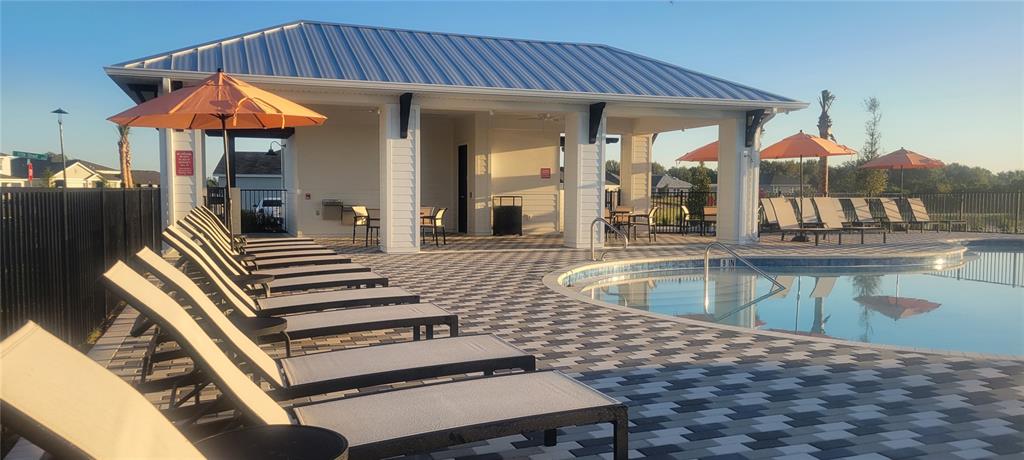 A swimming pool with lounge chairs and a covered patio area at sunset — 10924 37TH AVENUE EAST, PALMETTO, FL