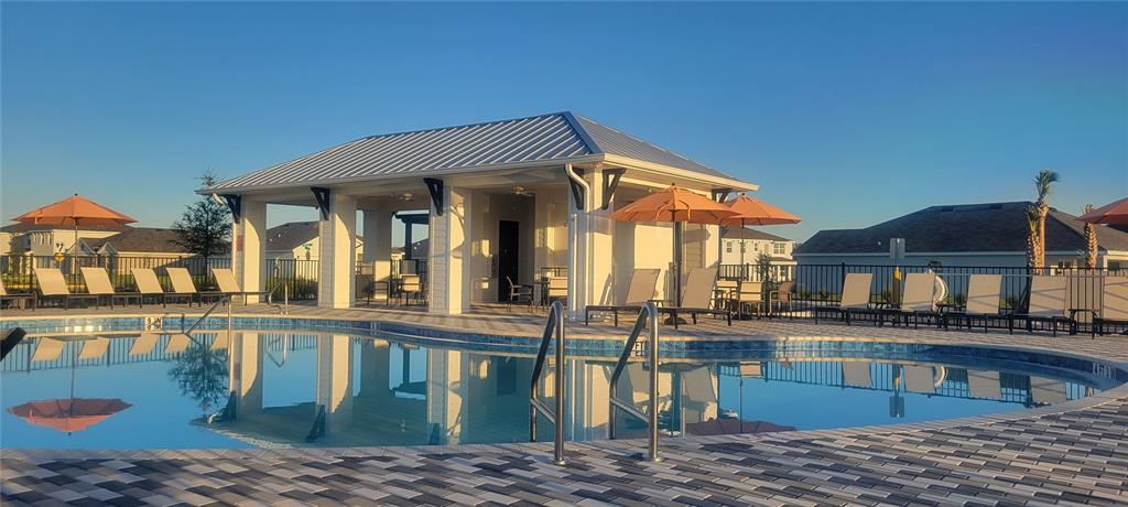 A swimming pool sits in front of a covered pavilion with lounge chairs and umbrellas — 10924 37TH AVENUE EAST, PALMETTO, FL