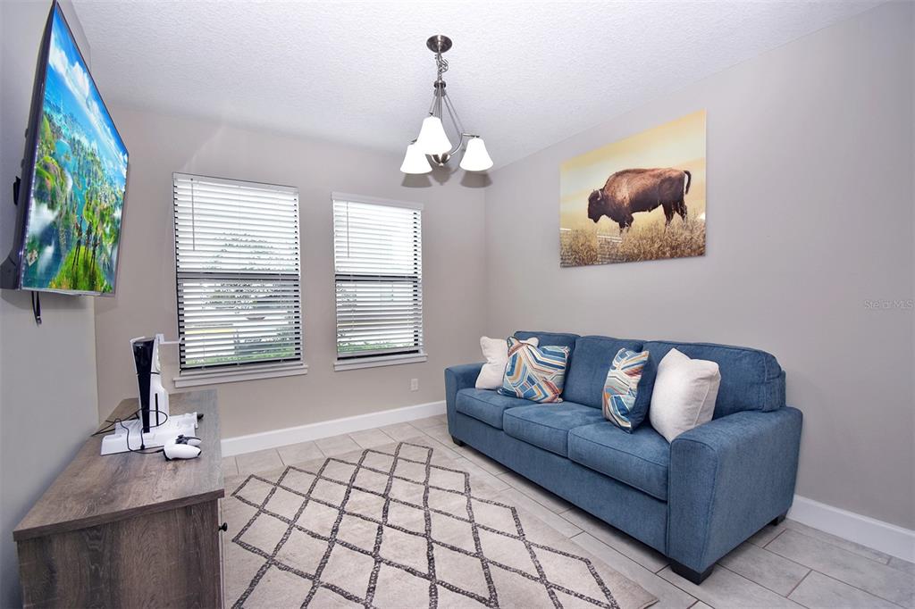 A living room features a blue sofa, a television, a rug, and a bison print — 4734 TERRA ESMERALDA, KISSIMMEE, FL