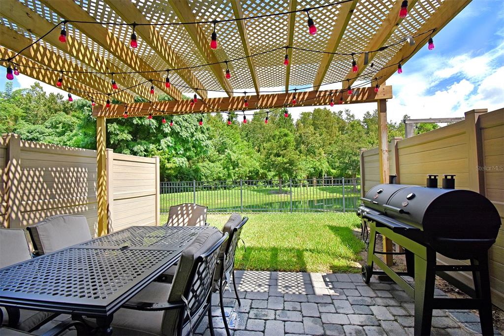A patio features a pergola with string lights, a dining set, and a charcoal grill — 4734 TERRA ESMERALDA, KISSIMMEE, FL