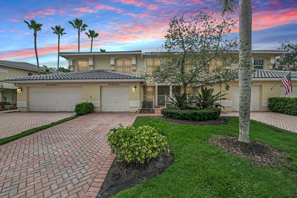 A two-story townhouse with a brick driveway, two garage doors, and a landscaped front yard — 9778 Bowline # 101, West Palm Beach FL 33411, WEST PALM BEACH, FL
