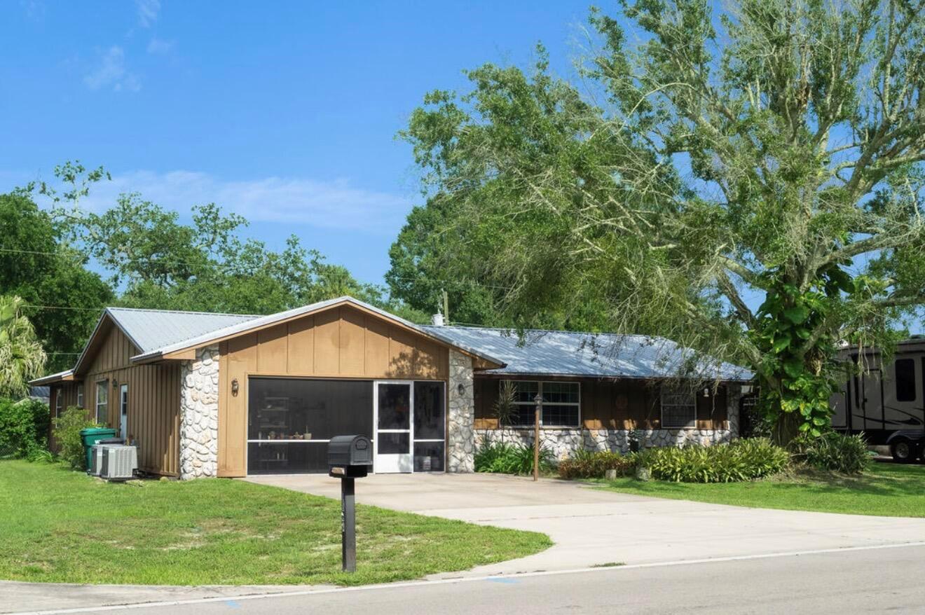 A single-story house with vertical wood siding, stone accents, and a metal roof — 1864 SW 24th Avenue, Okeechobee FL 34974, OKEECHOBEE, FL