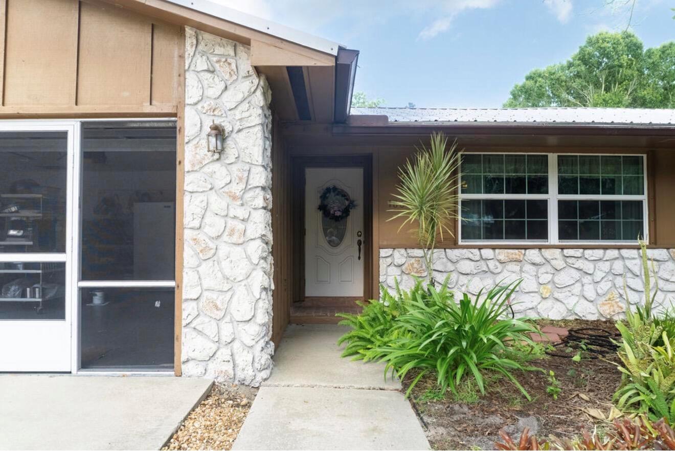 A house exterior features a stone facade, a white front door, and a screened porch — 1864 SW 24th Avenue, Okeechobee FL 34974, OKEECHOBEE, FL