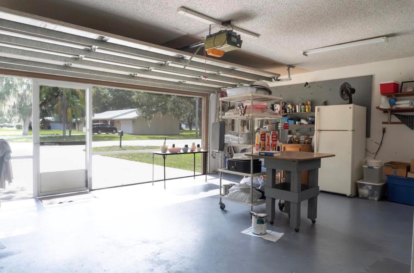 A garage with a concrete floor, a workbench, storage shelving, and an open door — 1864 SW 24th Avenue, Okeechobee FL 34974, OKEECHOBEE, FL