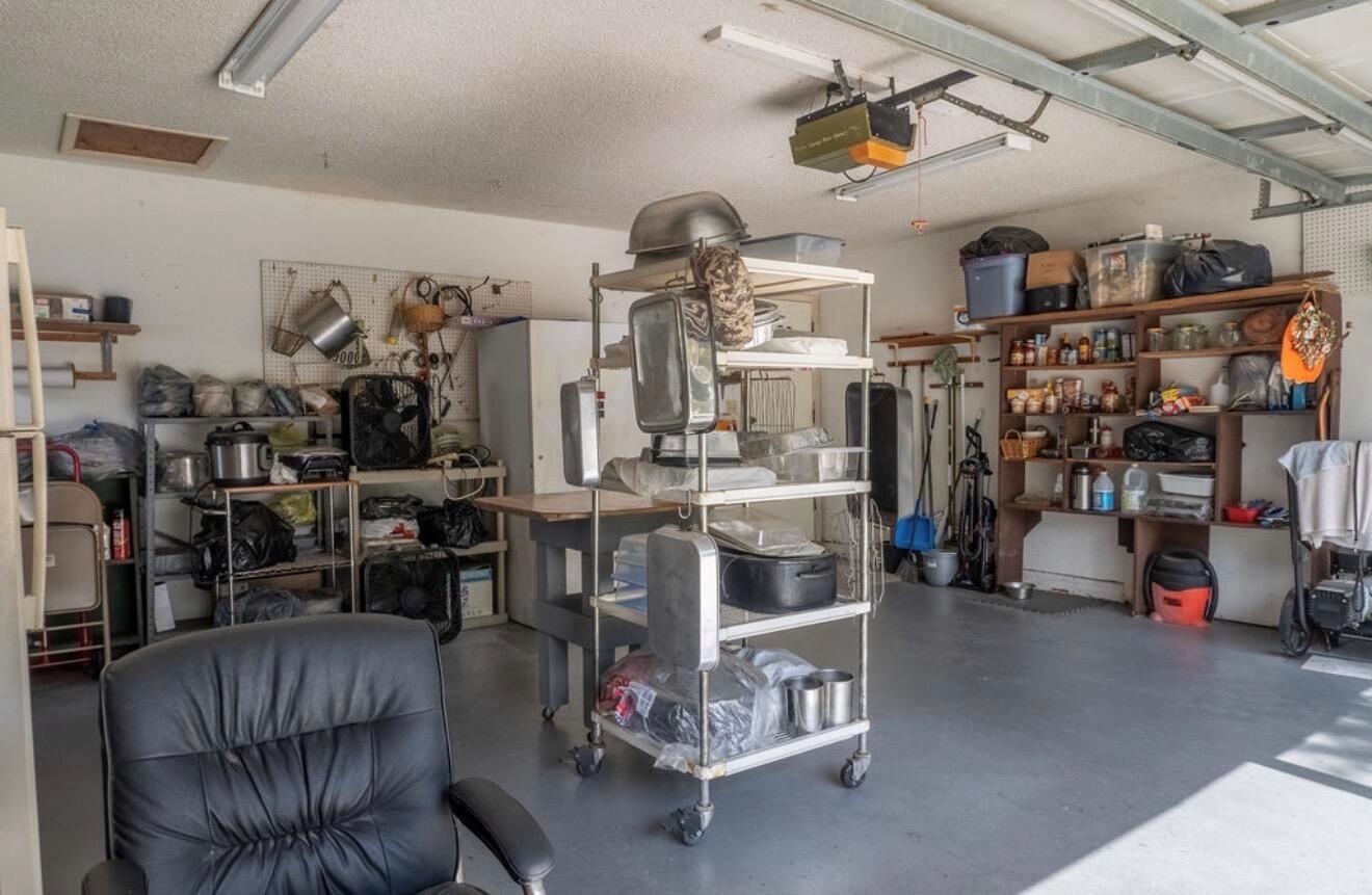 A garage with a rolling metal shelving unit, storage racks, and a black office chair — 1864 SW 24th Avenue, Okeechobee FL 34974, OKEECHOBEE, FL
