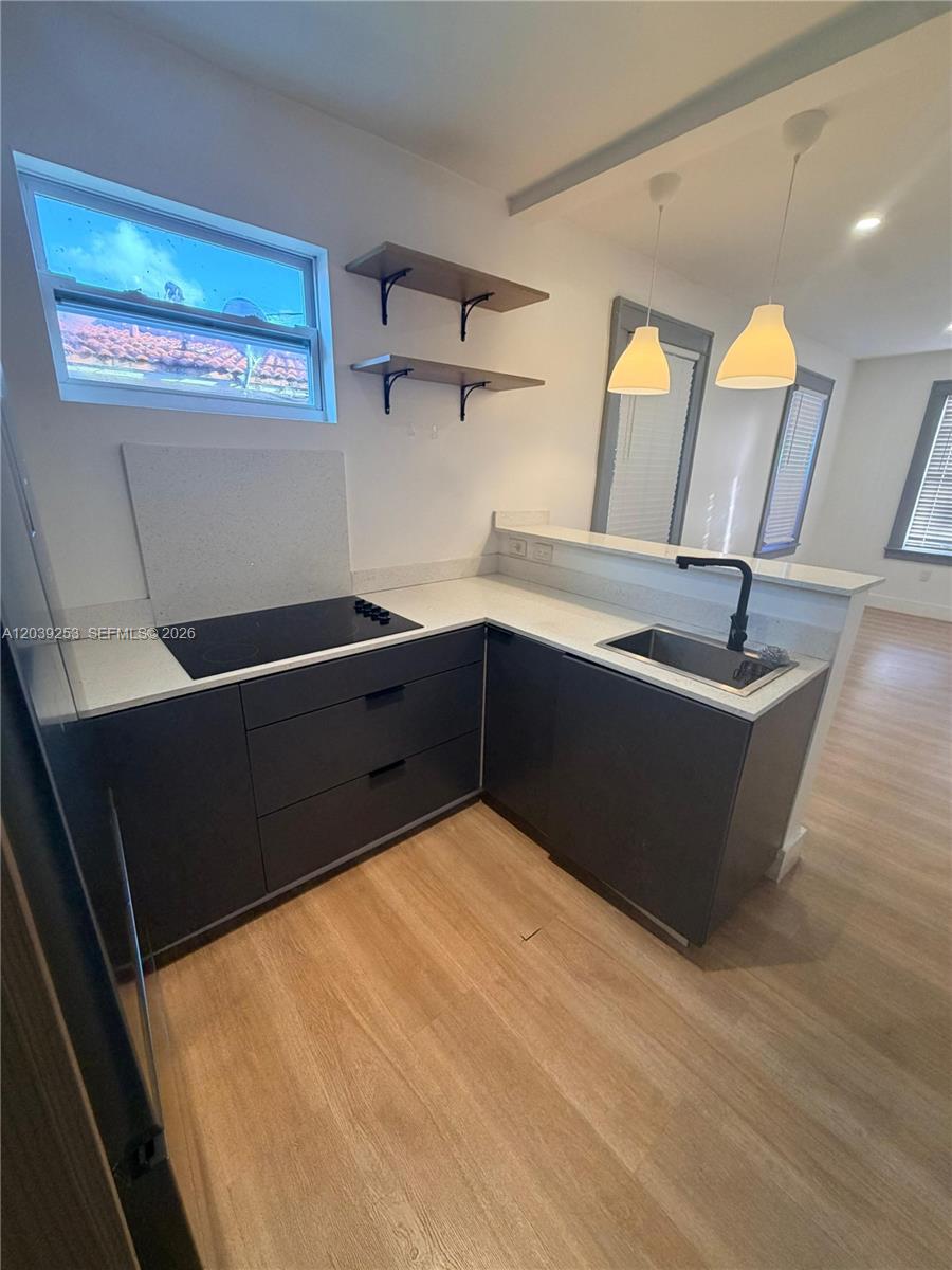 A small kitchen features dark grey cabinets, white countertops, a cooktop, and a sink — 453 NW 25th Ct # 1, Miami FL 33125, MIAMI, FL