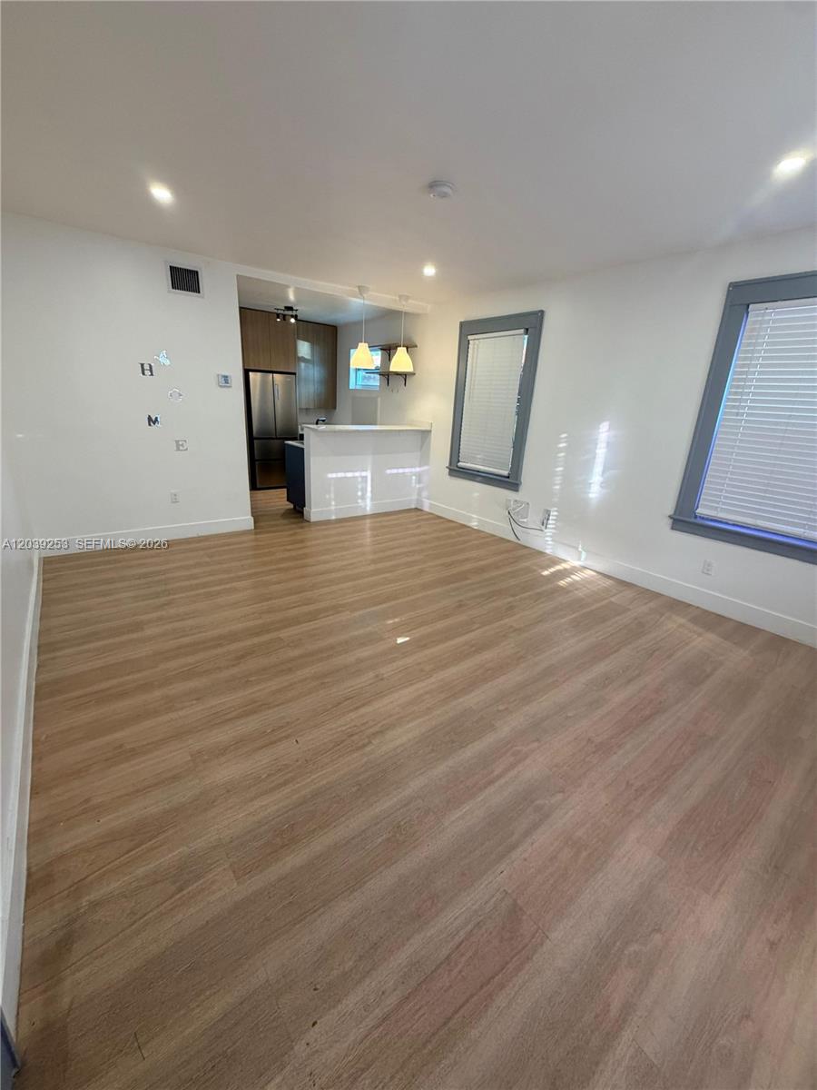 This living room features light wood-look flooring, white walls, and an open kitchen area — 453 NW 25th Ct # 1, Miami FL 33125, MIAMI, FL