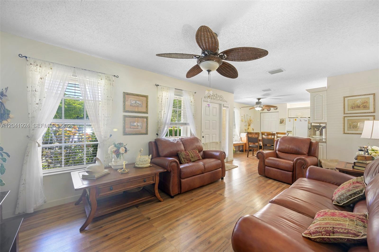 A living room features brown leather furniture, wood-look flooring, and a ceiling fan — 906 SW 8th Ave, Hallandale Beach FL 33009, HALLANDALE BEACH, FL