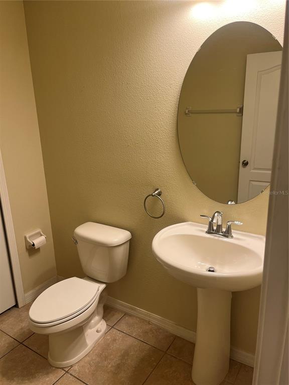 A small bathroom features a pedestal sink, an oval mirror, and a white toilet — 228 CARINA CIRCLE, SANFORD, FL