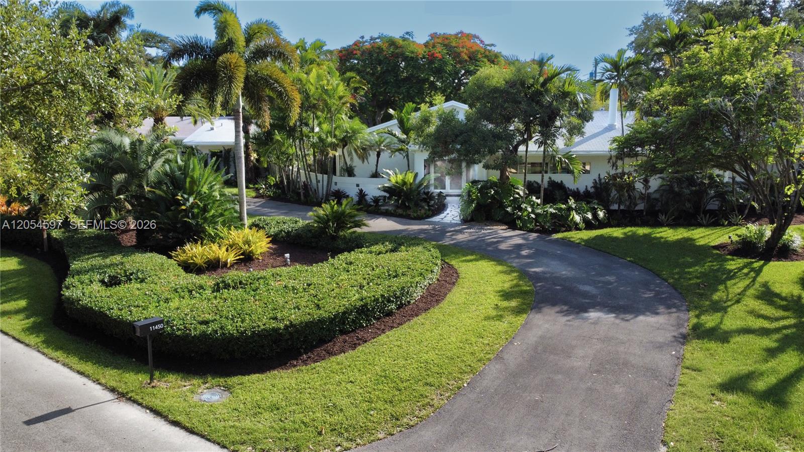 A curved driveway leads to a white house surrounded by lush tropical landscaping and trees — 11450 SW 92nd Ct, Miami FL 33176, MIAMI, FL