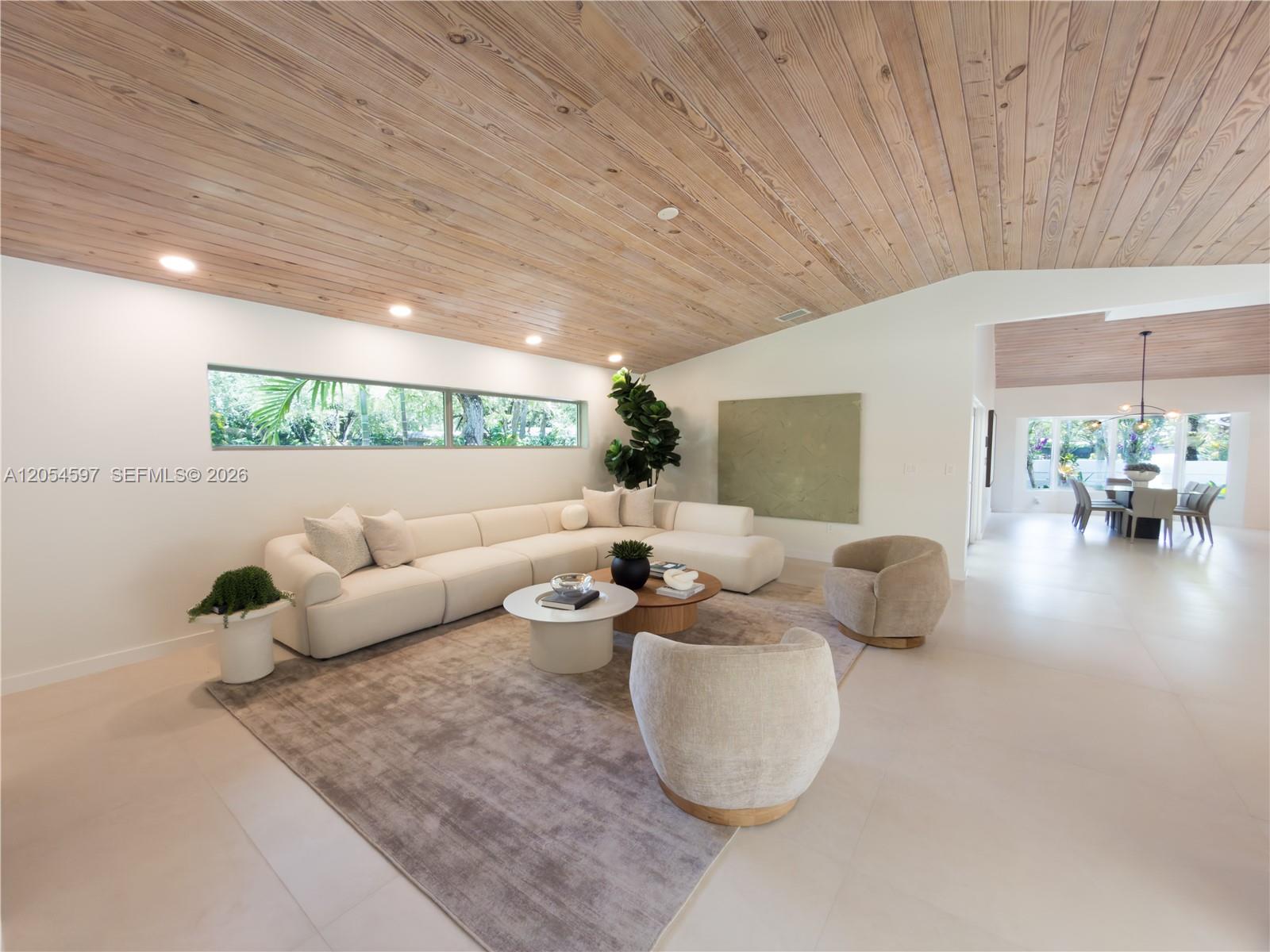 A modern living room features a large sectional sofa, wood-paneled ceiling, and a dining area — 11450 SW 92nd Ct, Miami FL 33176, MIAMI, FL