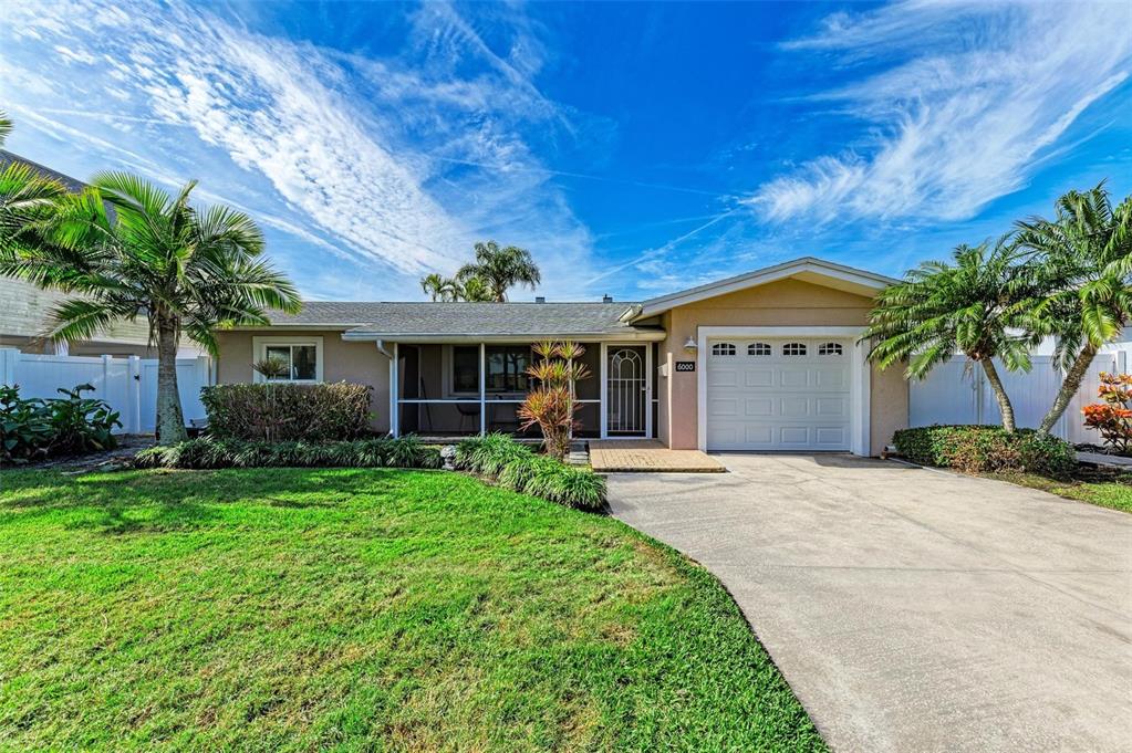 A single-story house with a white garage, a screened porch, and palm trees in front — 6000 BAYOU GRANDE BOULEVARD NE, ST PETERSBURG, FL