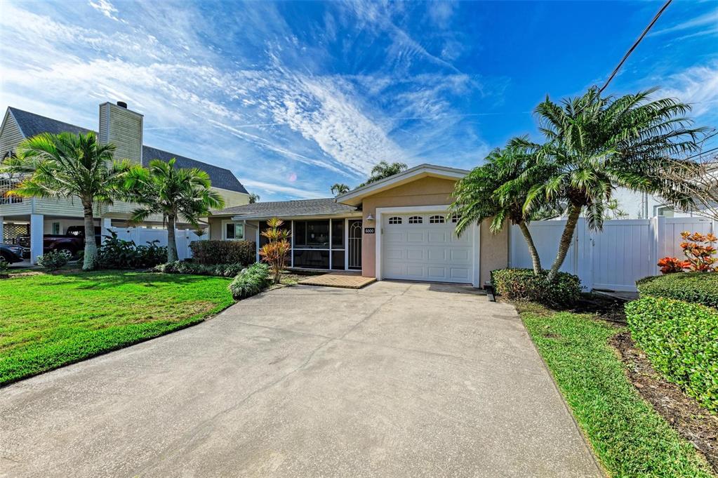 A single-story house with a white garage door, concrete driveway, and palm trees — 6000 BAYOU GRANDE BOULEVARD NE, ST PETERSBURG, FL