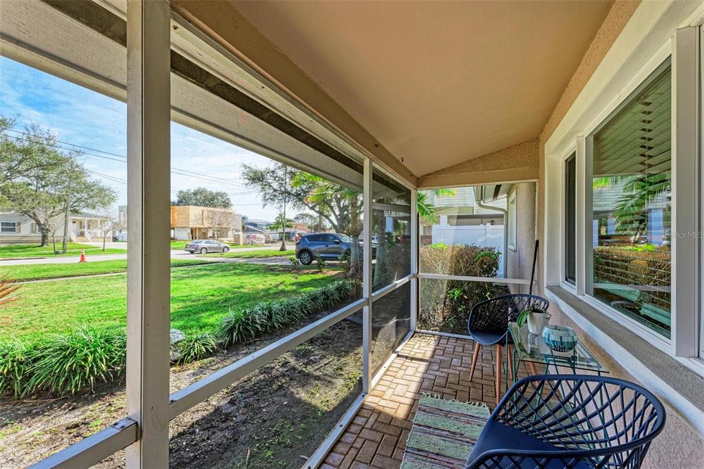 A screened-in porch with brick flooring overlooks a grassy yard and a residential street — 6000 BAYOU GRANDE BOULEVARD NE, ST PETERSBURG, FL