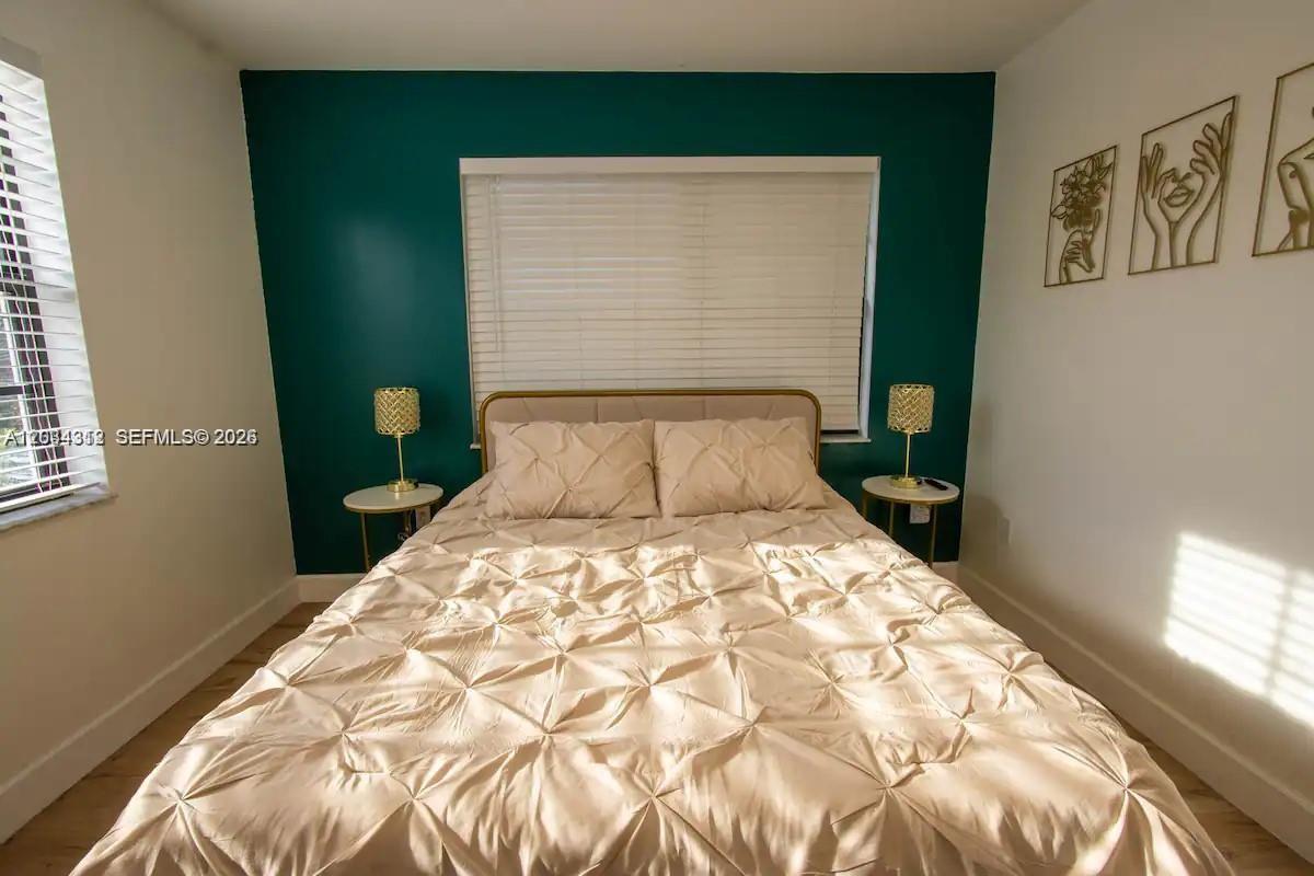 A bedroom features a bed with a gold tufted headboard against a dark teal wall — 5911 SW 5th Ter # B, Miami FL 33144, MIAMI, FL