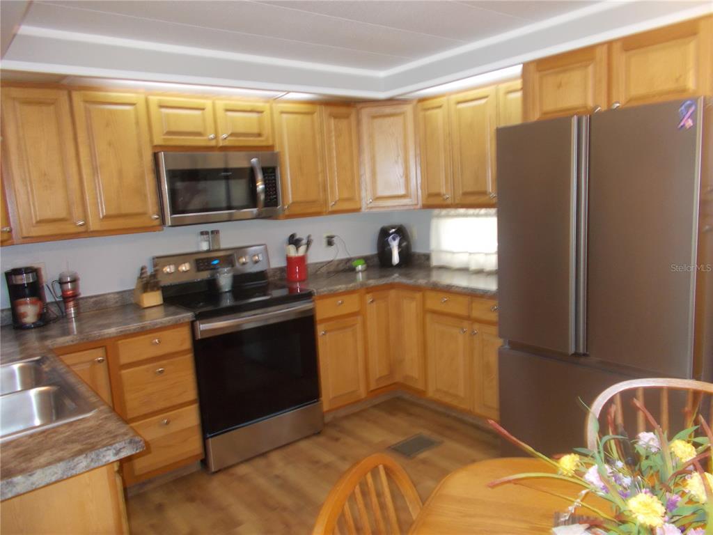 A kitchen features light wood cabinets, stainless steel appliances, and a dark laminate countertop — 5755 HOLIDAY PARK BOULEVARD, NORTH PORT, FL