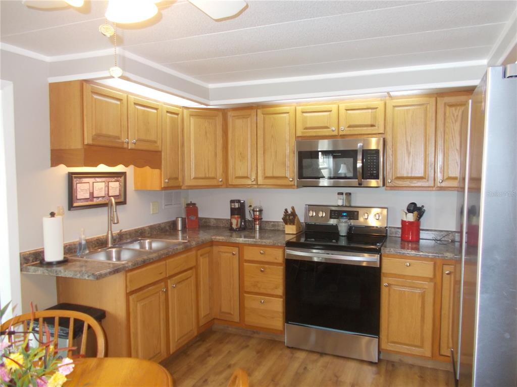 A kitchen with oak cabinets, stainless steel appliances, and laminate countertops — 5755 HOLIDAY PARK BOULEVARD, NORTH PORT, FL