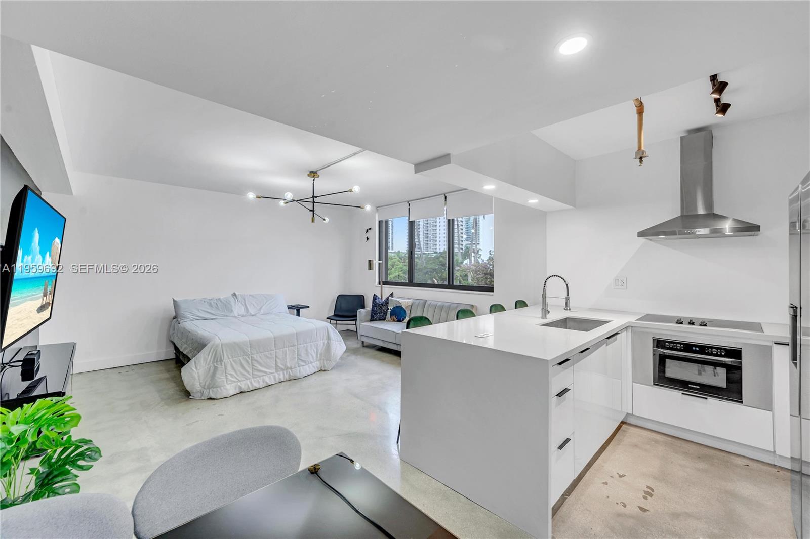 A studio apartment features a kitchen with white cabinets, a bed, and a living area — 540 Brickell Key Dr # 409, Miami FL 33131, MIAMI, FL