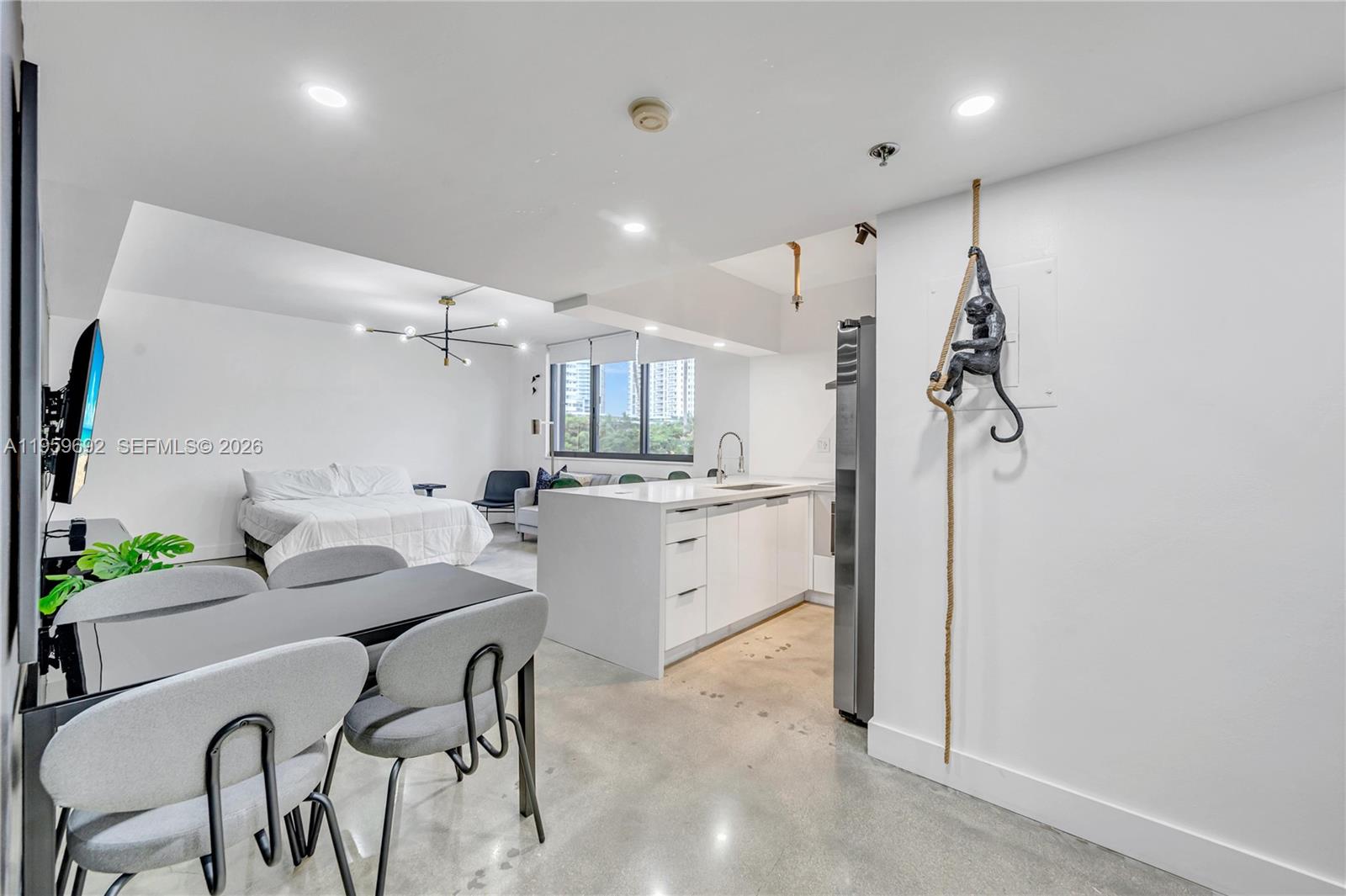 A studio apartment features a kitchen island, dining area, bed, and a decorative wall monkey — 540 Brickell Key Dr # 409, Miami FL 33131, MIAMI, FL