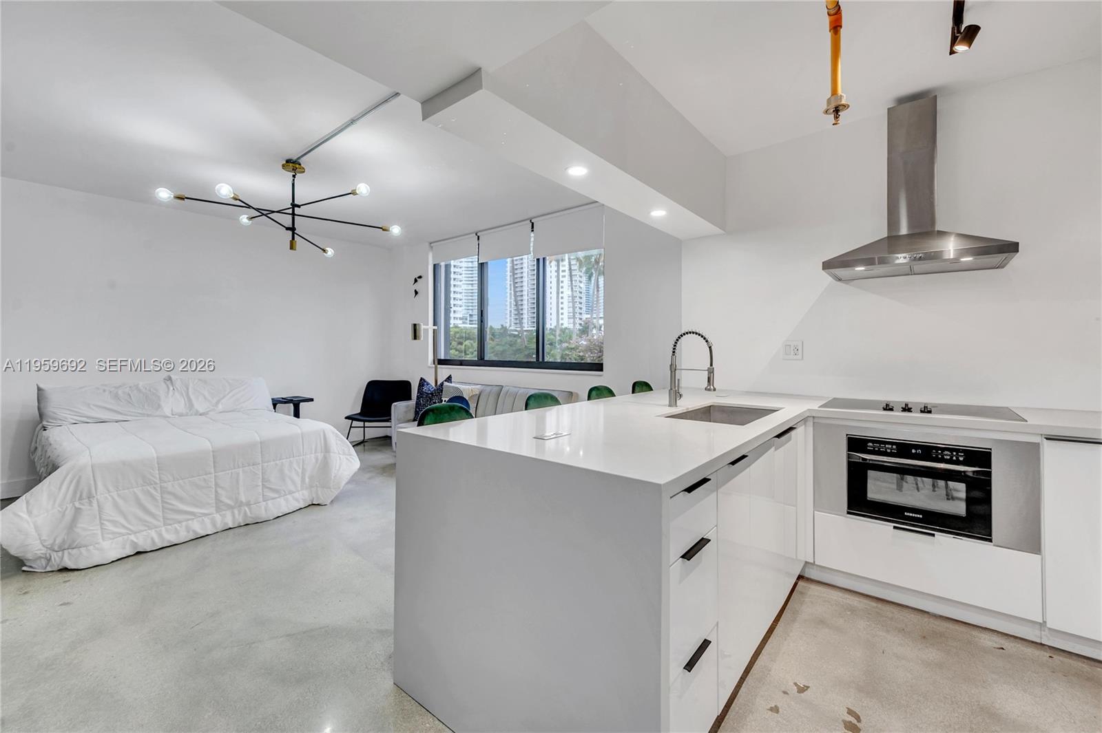 A studio apartment features a white kitchen island, stainless steel appliances, and a bed area — 540 Brickell Key Dr # 409, Miami FL 33131, MIAMI, FL