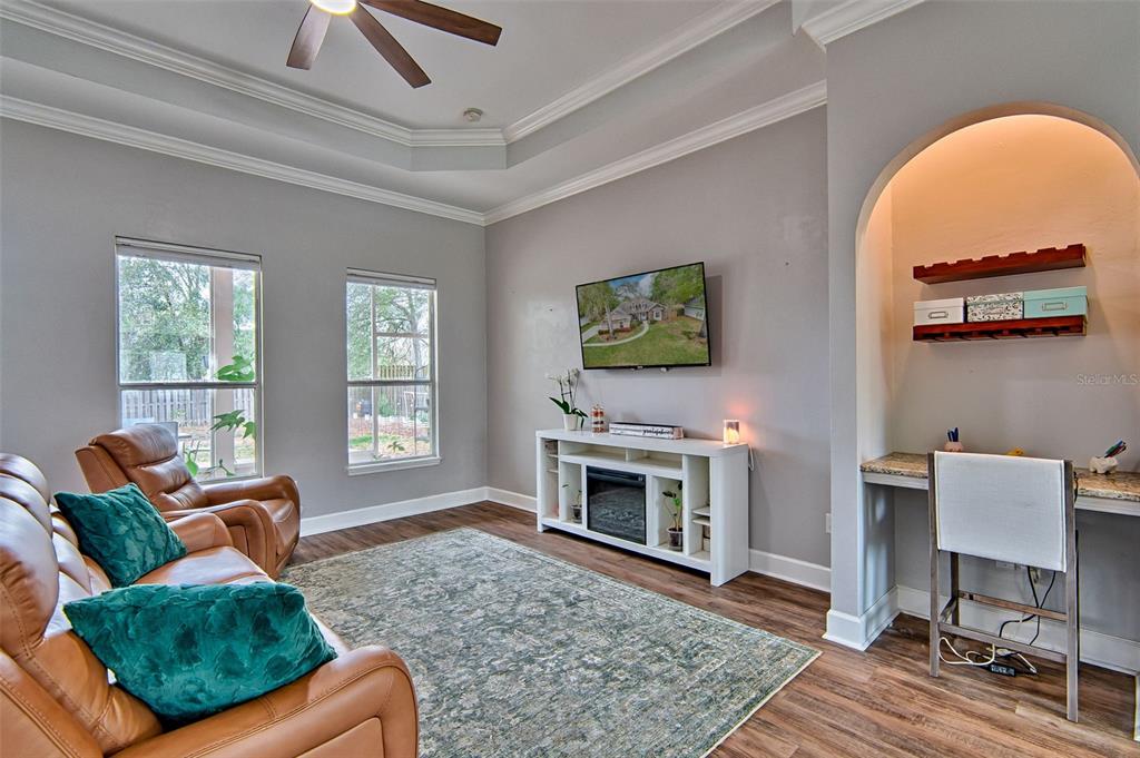 A living room features a tray ceiling, brown leather furniture, a fireplace console, and a built-in desk — 15122 NW 149TH ROAD, ALACHUA, FL