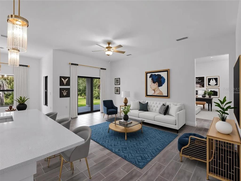 A modern living room with a white sofa, blue area rug, and kitchen island — 17339 ELMWOOD AVENUE, PORT CHARLOTTE, FL