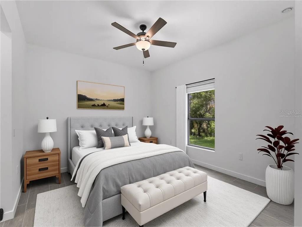 A bedroom features a gray upholstered bed, a tufted bench, and a ceiling fan — 17339 ELMWOOD AVENUE, PORT CHARLOTTE, FL