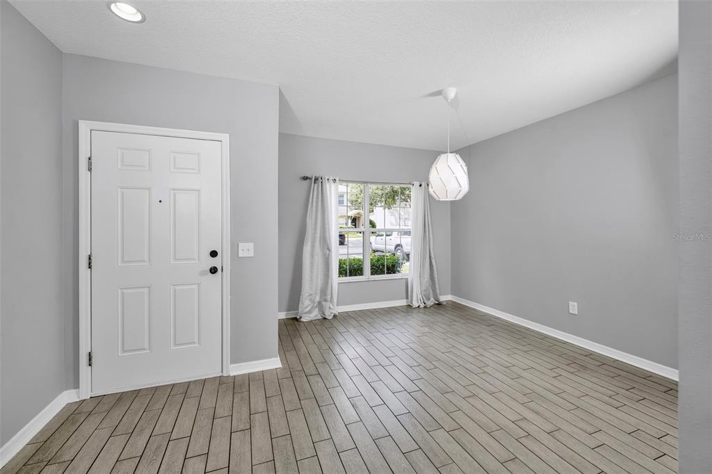 A dining room features gray walls, wood-look tile flooring, a white door, and a pendant light — 5842 FISHHAWK RIDGE DRIVE, LITHIA, FL