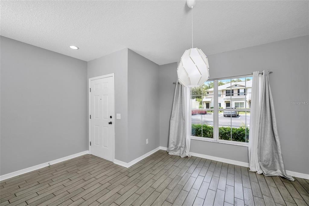 A dining area features gray walls, wood-look tile flooring, a modern pendant light, and windows — 5842 FISHHAWK RIDGE DRIVE, LITHIA, FL