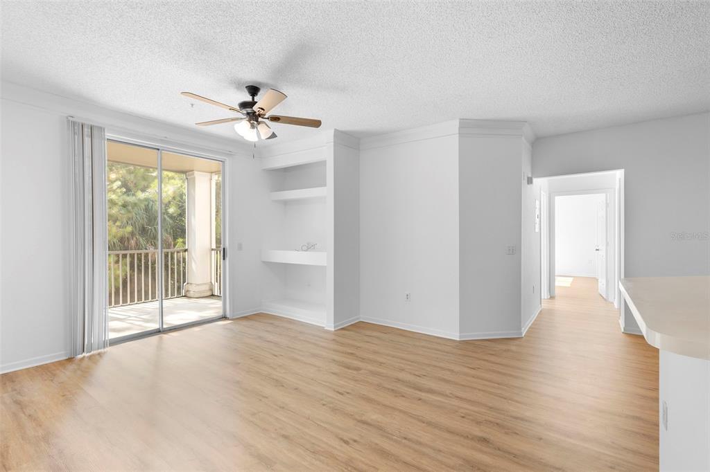A living room with light wood flooring, a ceiling fan, built-in shelves, and a sliding door — 13037 MULBERRY PARK DRIVE UNIT 529, ORLANDO, FL