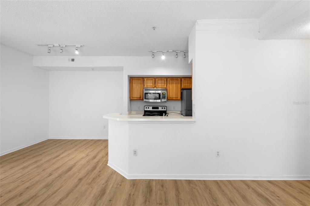 A kitchen with wood cabinets and stainless steel appliances overlooks an open living area — 13037 MULBERRY PARK DRIVE UNIT 529, ORLANDO, FL